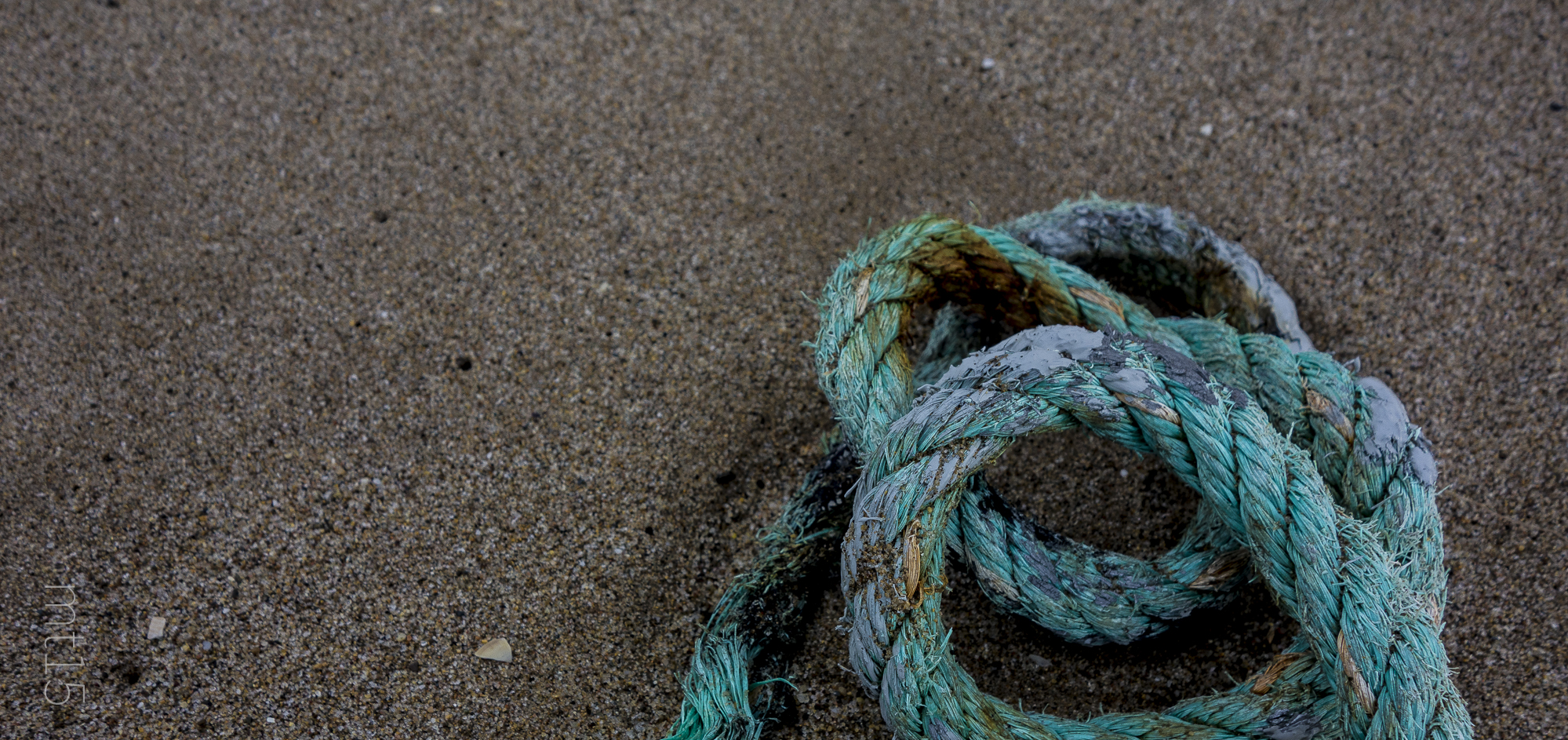 a yarn rope laying on top of a sand covered ground