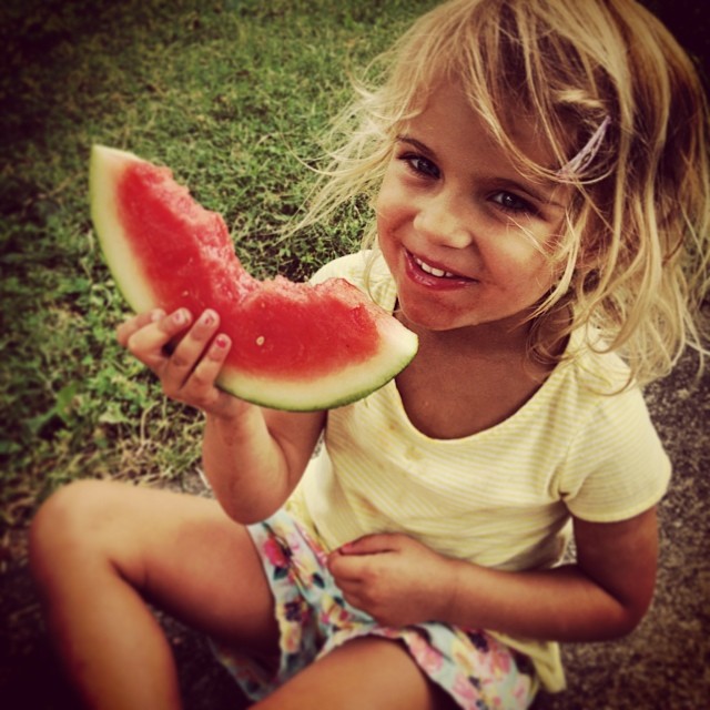 little girl eating a watermelon on the ground