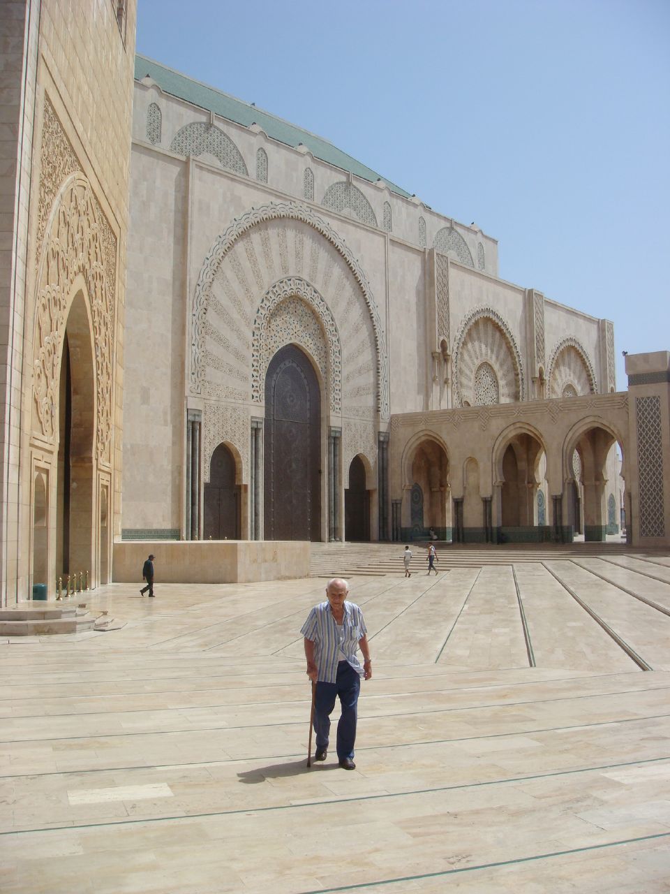 an older man is standing in the middle of a courtyard