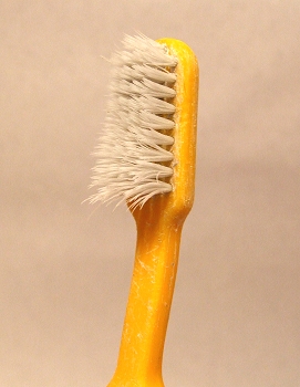 a plastic tube filled with a yellow plastic brush