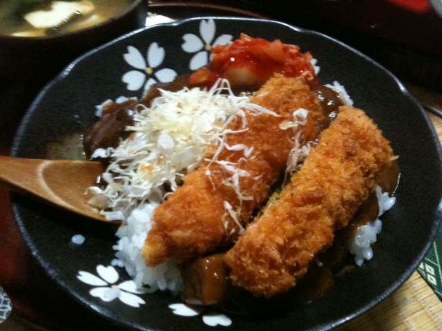 a fried chicken with sauce and white rice in a black bowl