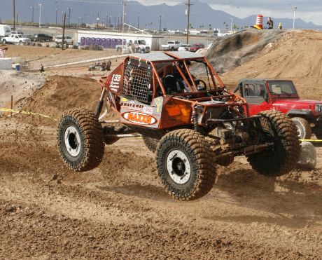 a red truck with two large wheels is going around a hill