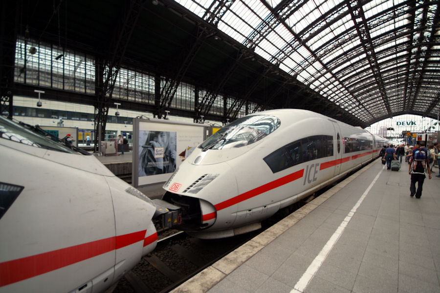 people are waiting at a train station as a bullet train pulls up to the platform