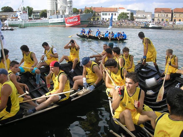 a large group of men and women rowing a boat in the water