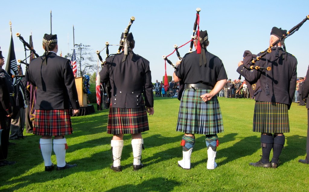 the pipers in kilts are marching in formation