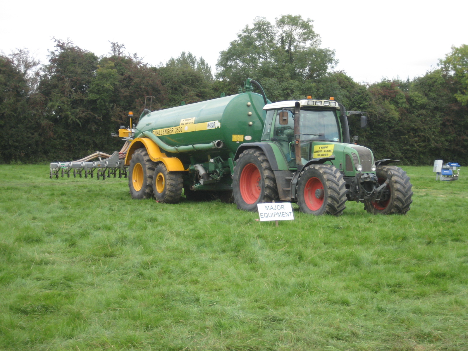 a tractor with some large tires parked in the grass