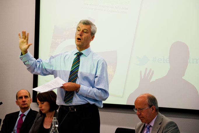 a man standing next to a projection screen while holding a paper