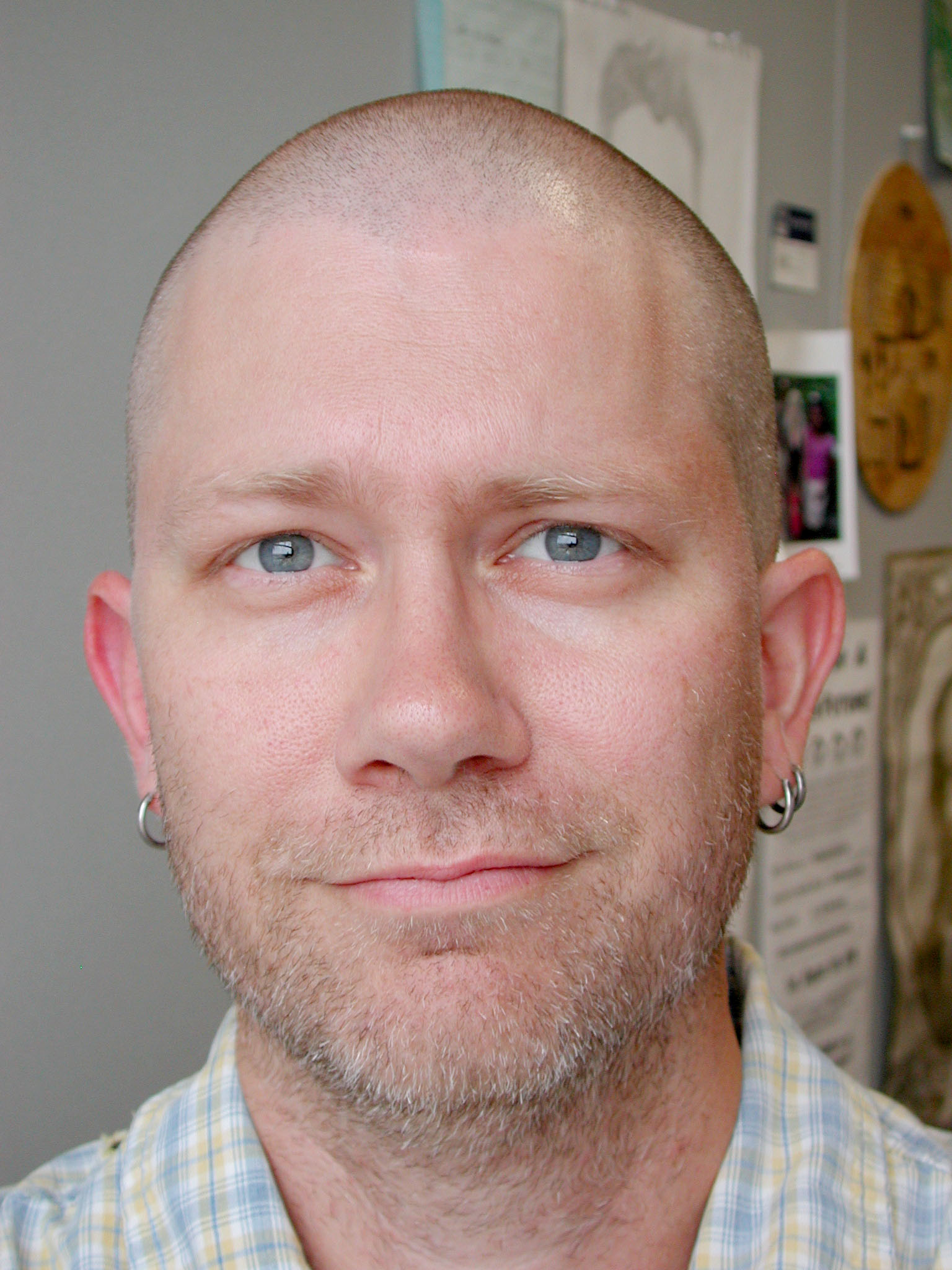 a bald man looking at the camera with ear buds