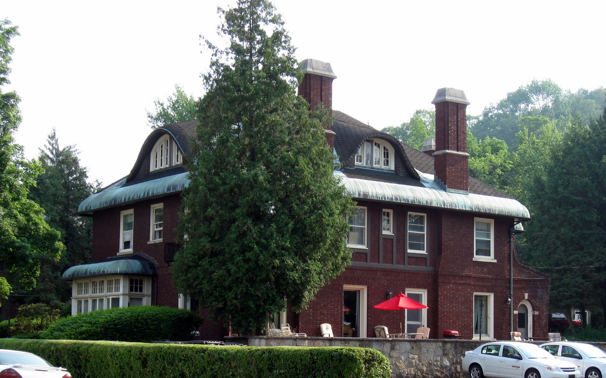 the building in the middle of the woods has red umbrellas and two parked cars