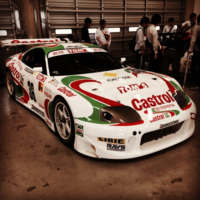 a white sports car with red, green, and yellow painted stripes in a garage