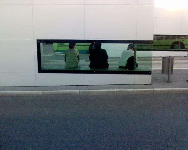 two people in front of a building with the reflection of them on the glass