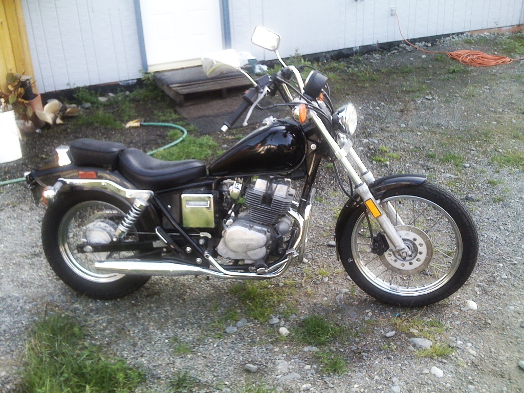 a motorbike parked on a gravel area in front of a building