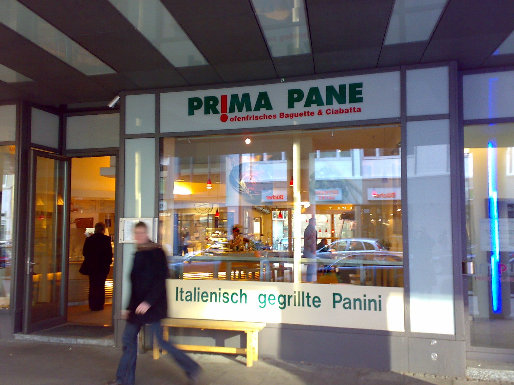 the front entrance to a store showing a man in the reflection