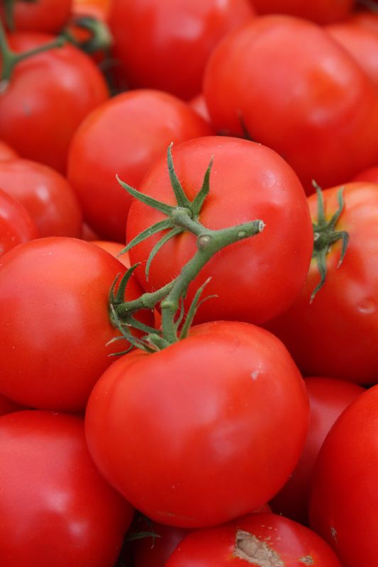 many tomatoes are piled together on the table