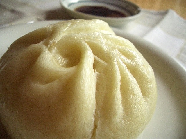 a chinese dumpling with sauce on the side