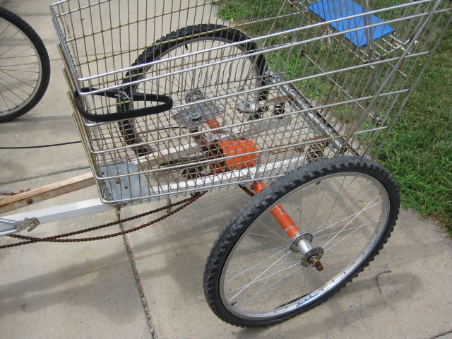 a bicycle with orange wheels sits parked next to a fence