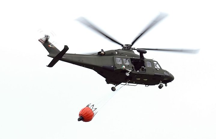 a military helicopter is being lifted by a man