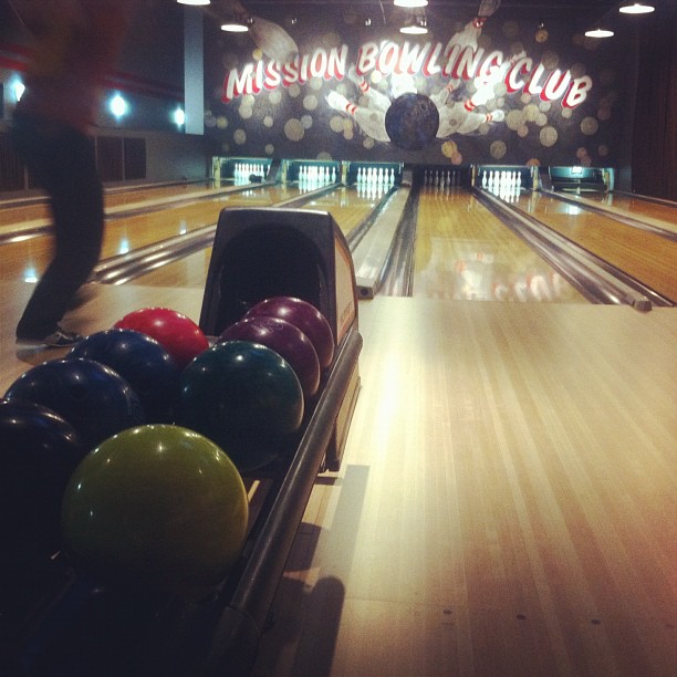a man riding a bowling ball down a bowling alley
