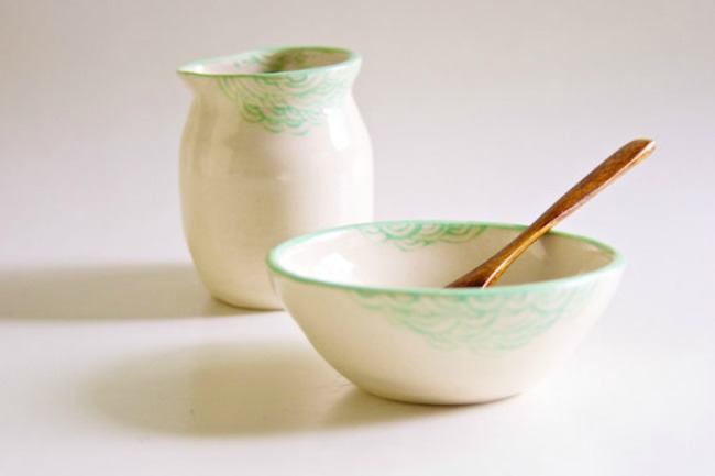 two white bowls with green designs and a gold spoon