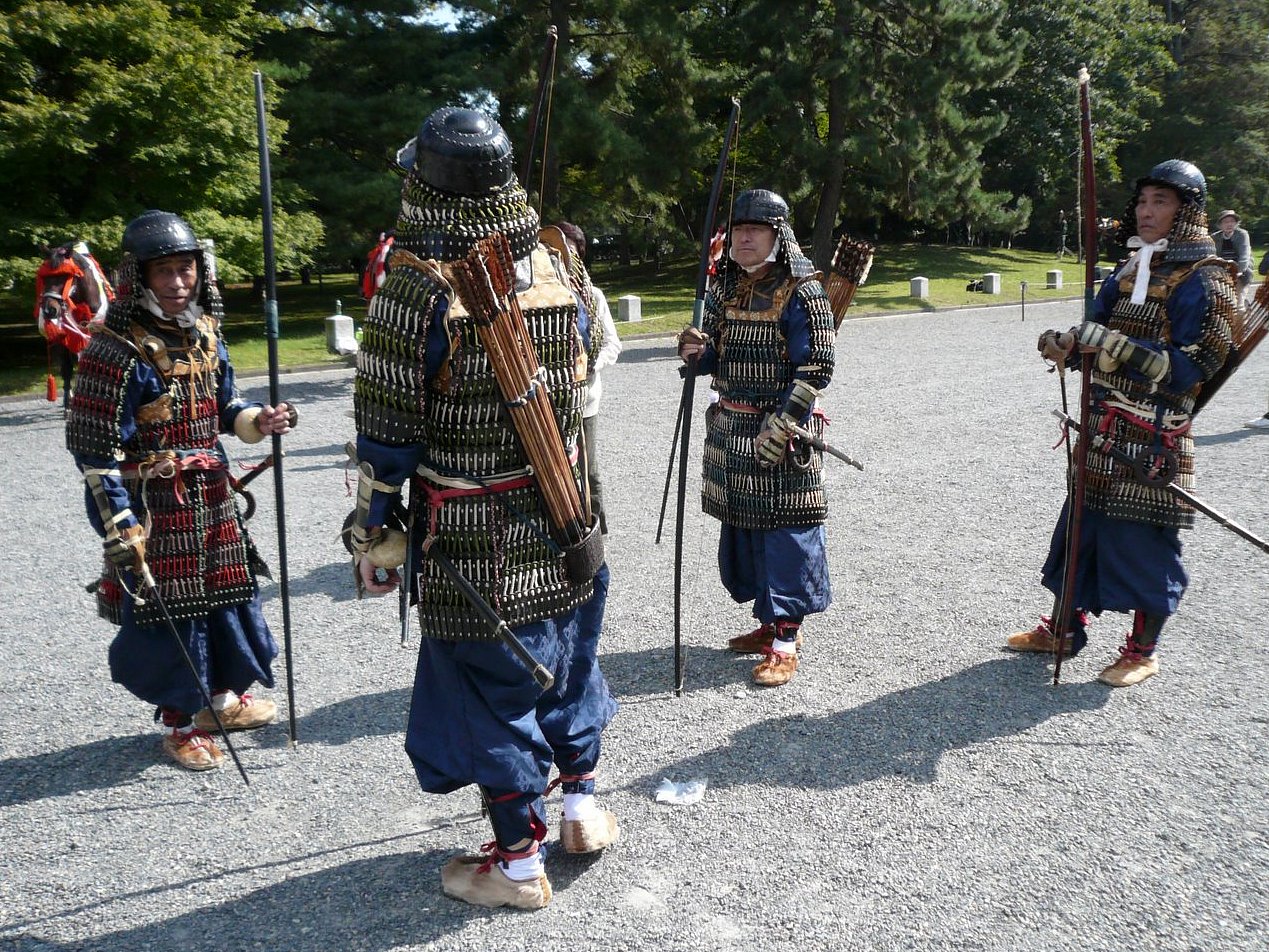 four people wearing armor while standing in front of a park