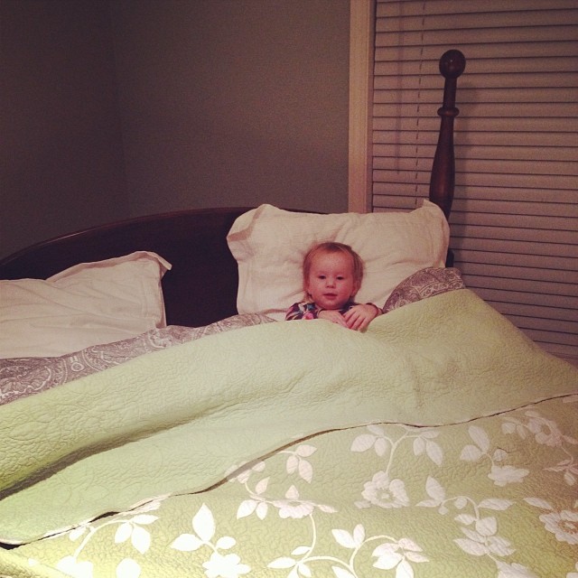 the young child is hiding behind the covers of his bed