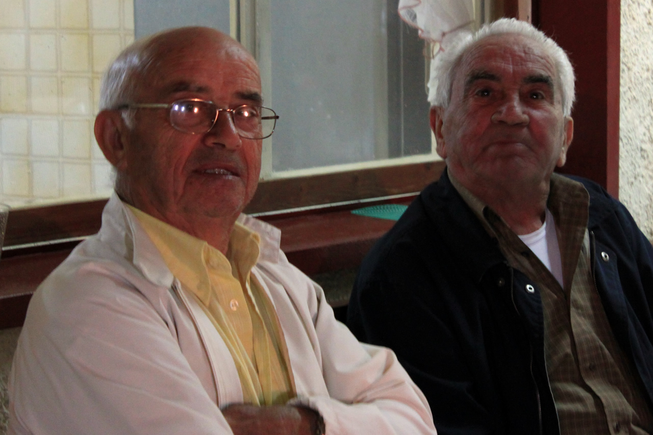 two older men sit and smile at the camera