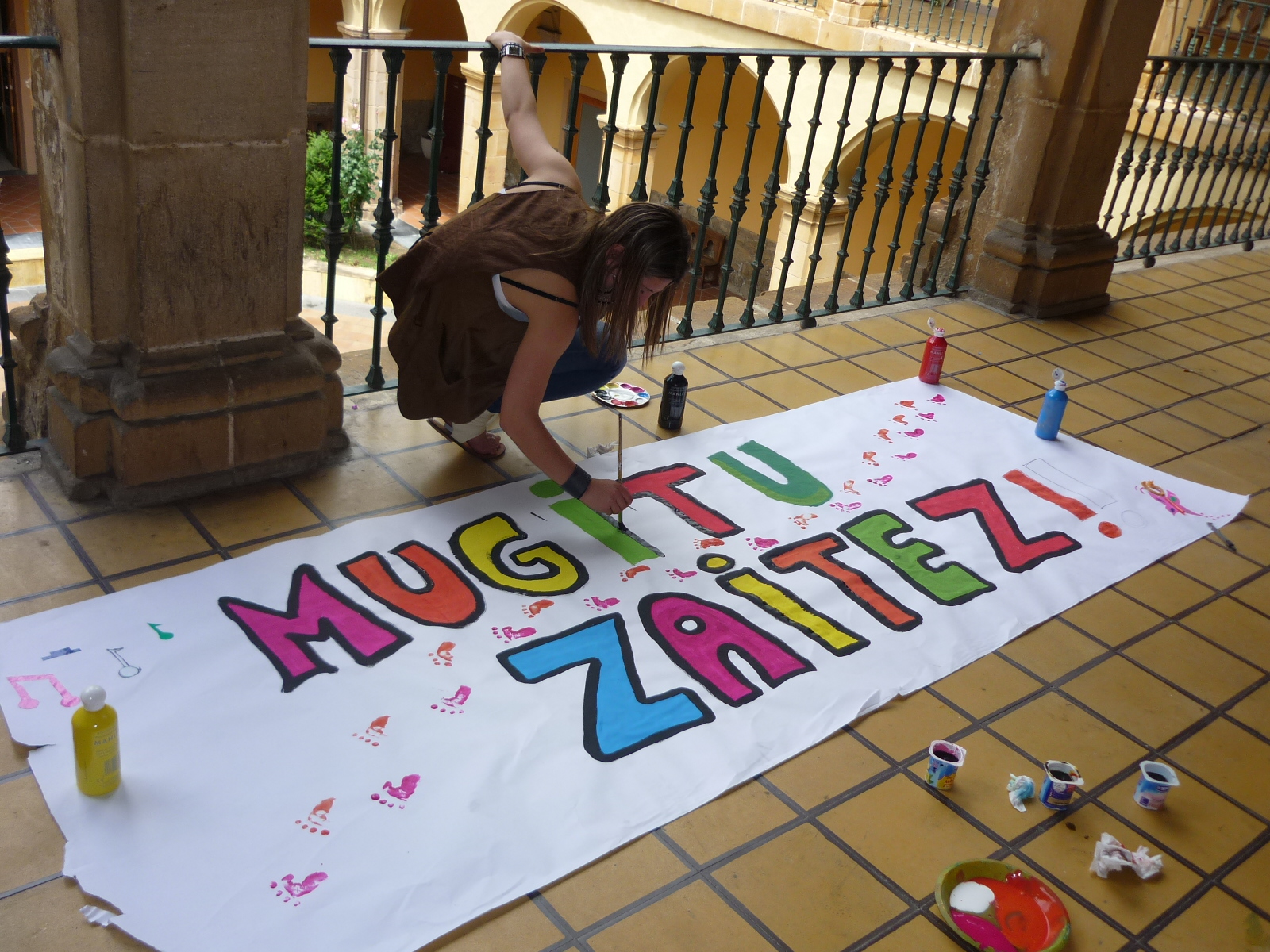 a woman writes on the front of a large sign with letters and shapes