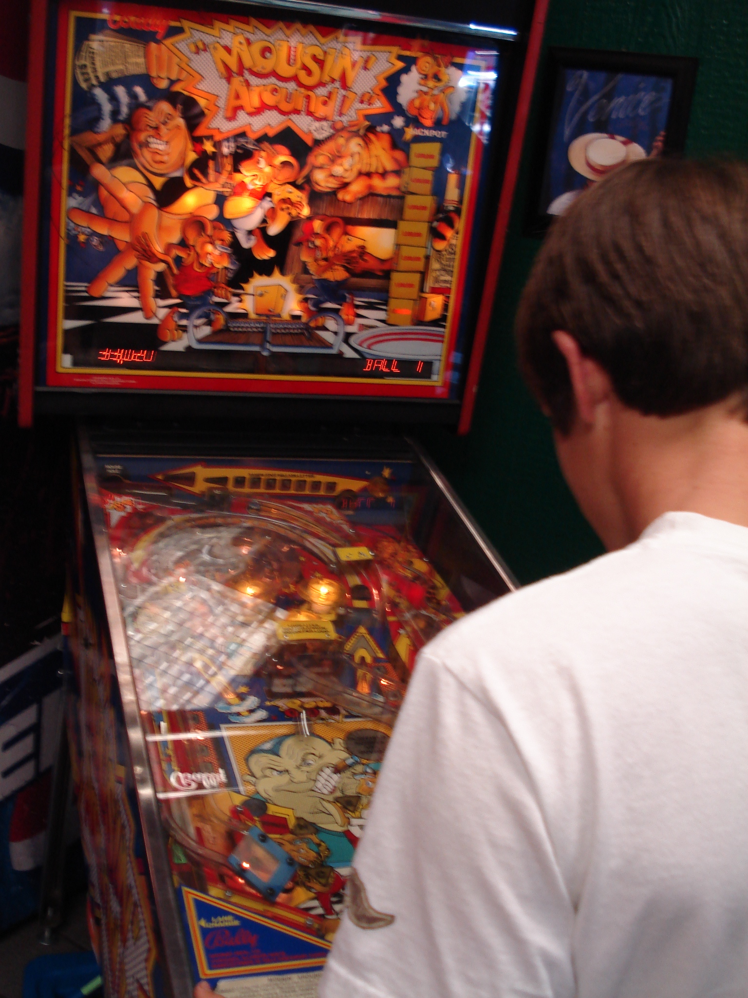 a man is playing pinball inside of the game room