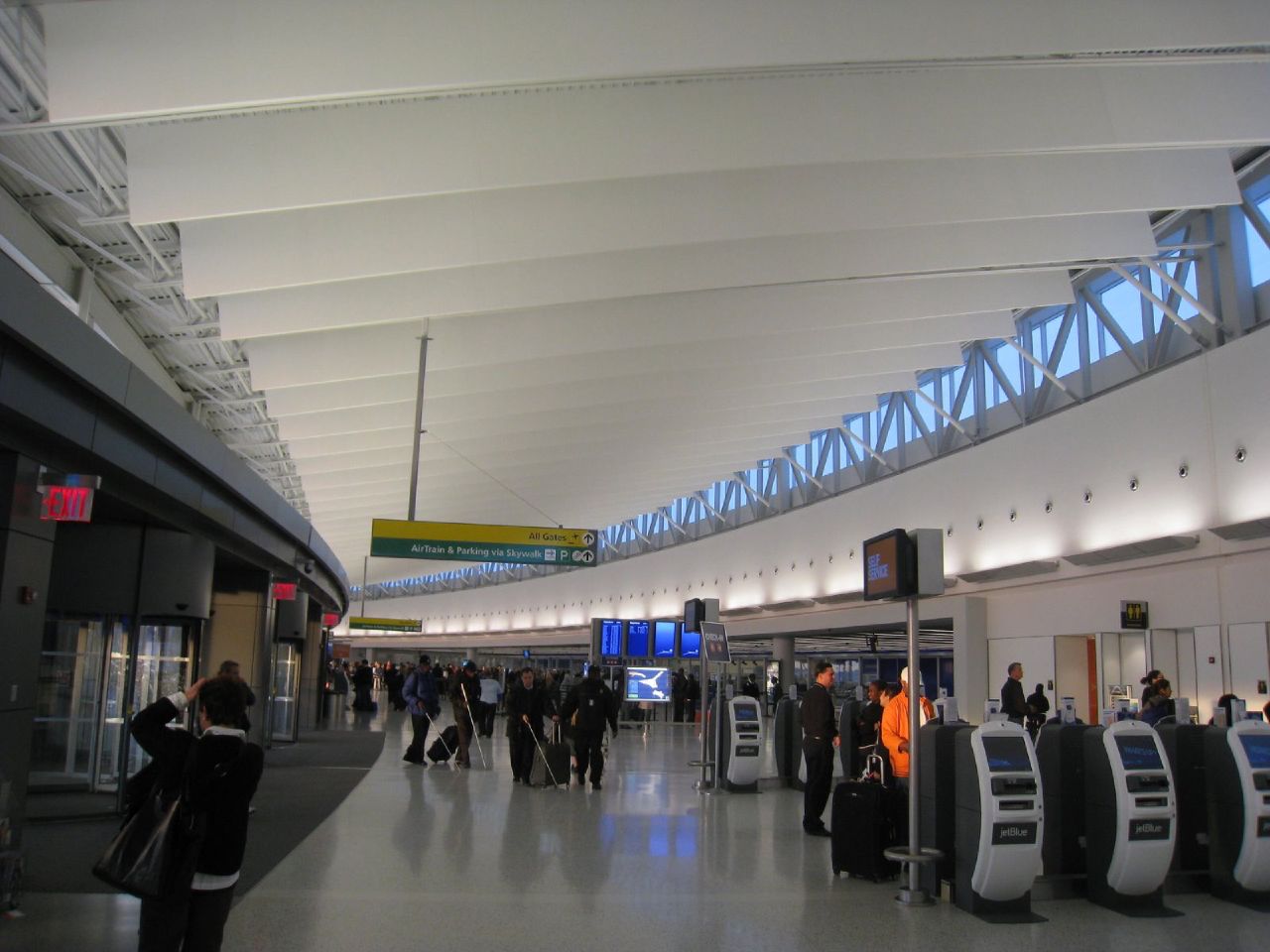 people walk along an airport concourse in the evening