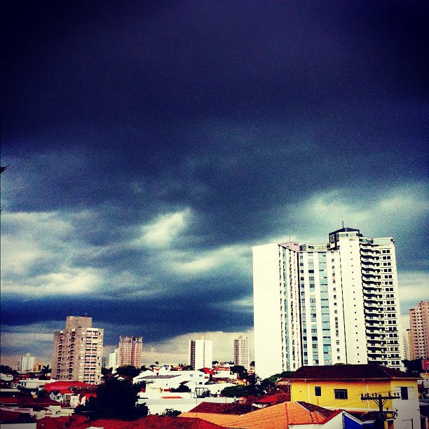 some tall buildings with lots of dark clouds above