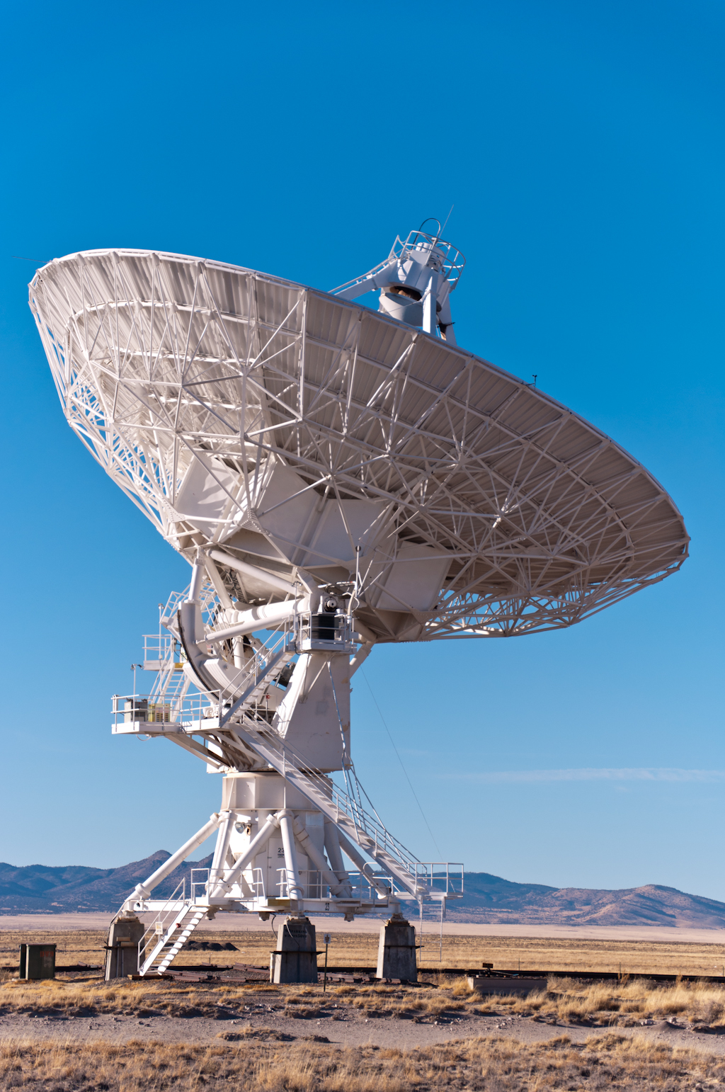 a very big antenna dish outside by some desert