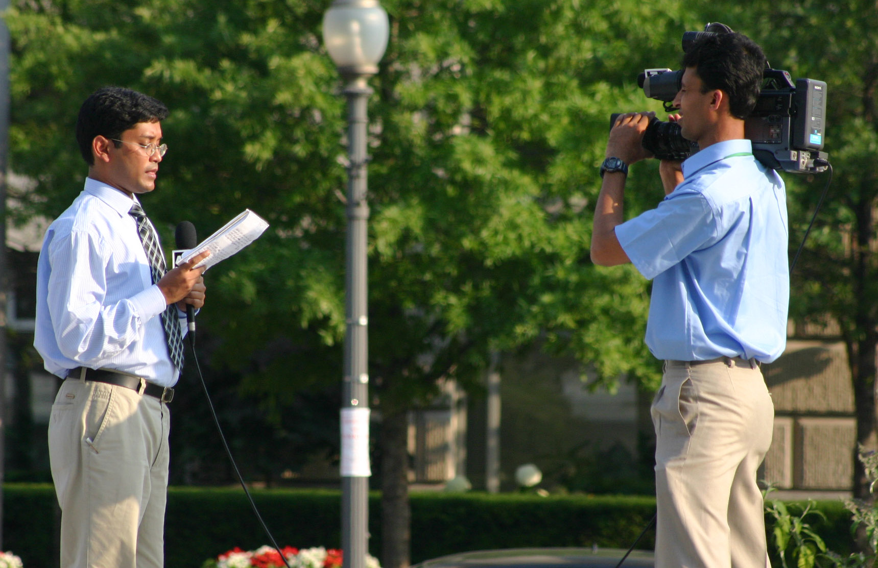 there are two men with cameras talking on the same street