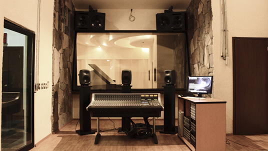 a home recording studio with equipment including an audio mixing desk and guitar
