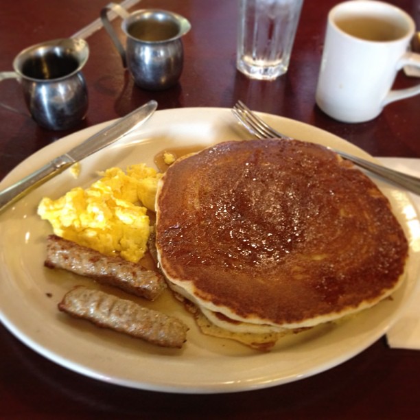 a breakfast plate of eggs, sausage, and pancakes