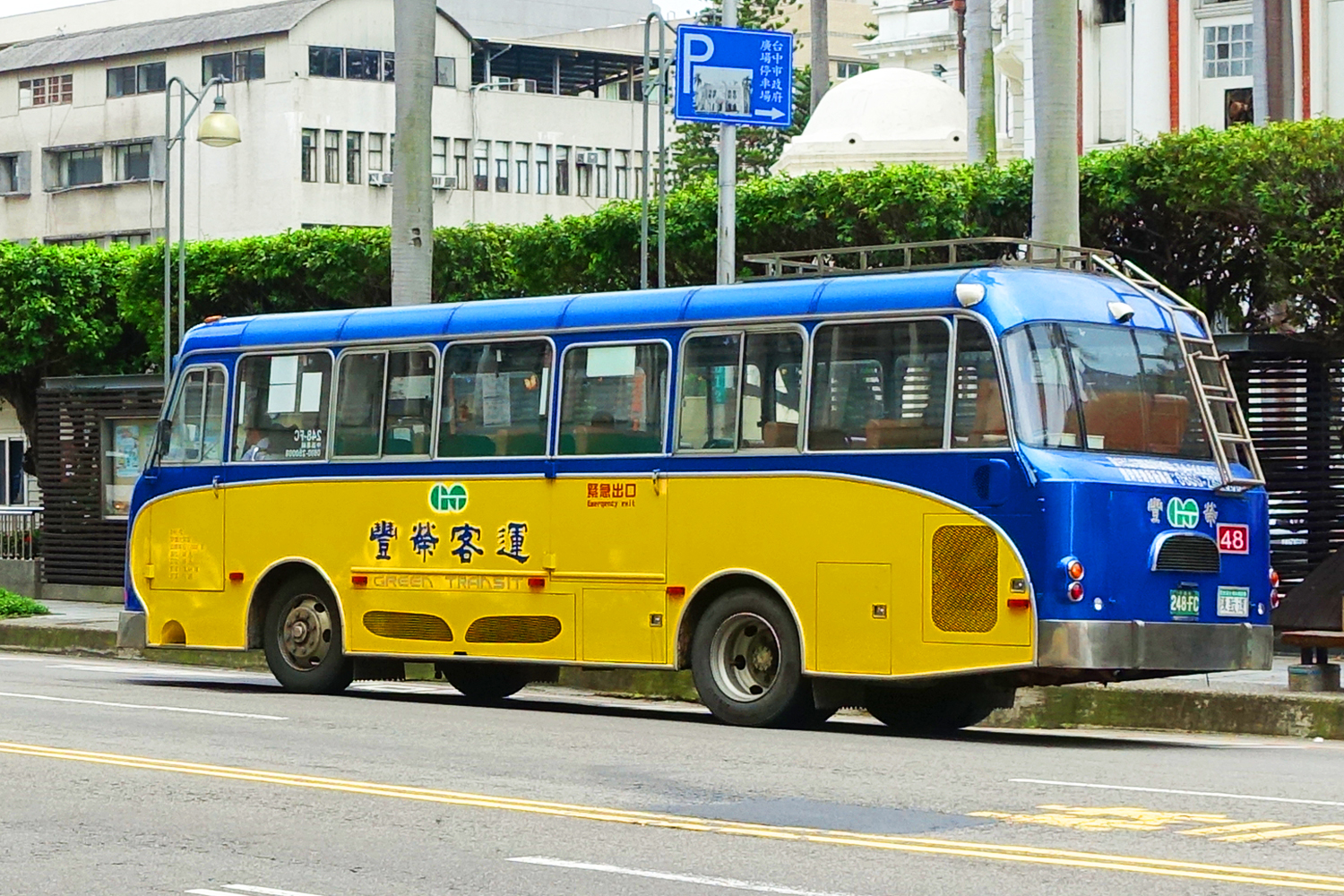 a yellow and blue bus is parked along the side of the road