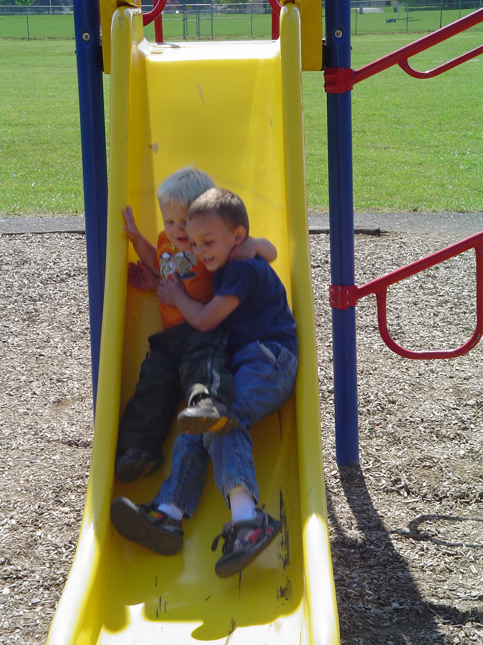 two s sitting on the slide at a park