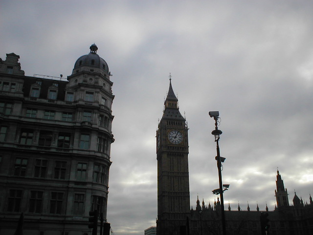 a clock tower against a cloudy sky and some buildings