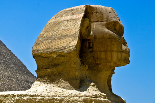a large statue in the desert with two pyramids