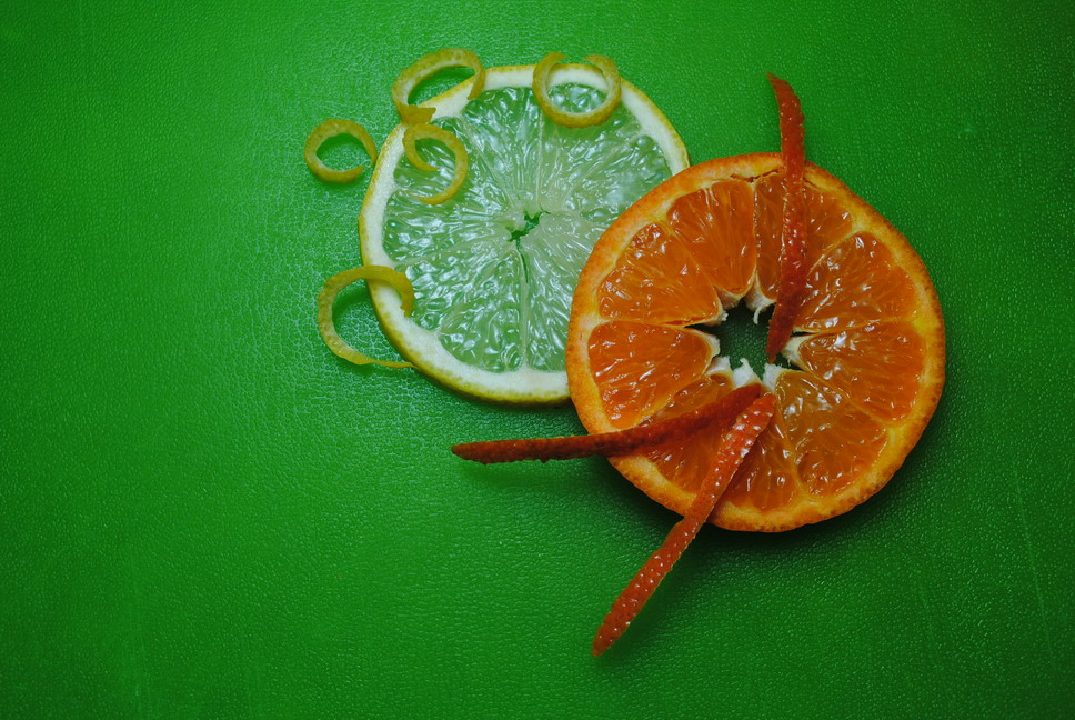 a sliced orange sitting next to scissors on a green table