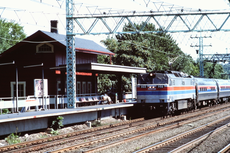 a blue, red and white train passing a train station