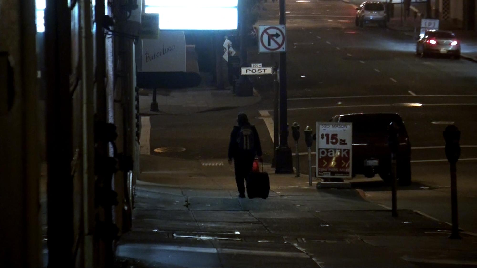 a person walking down the side walk next to traffic
