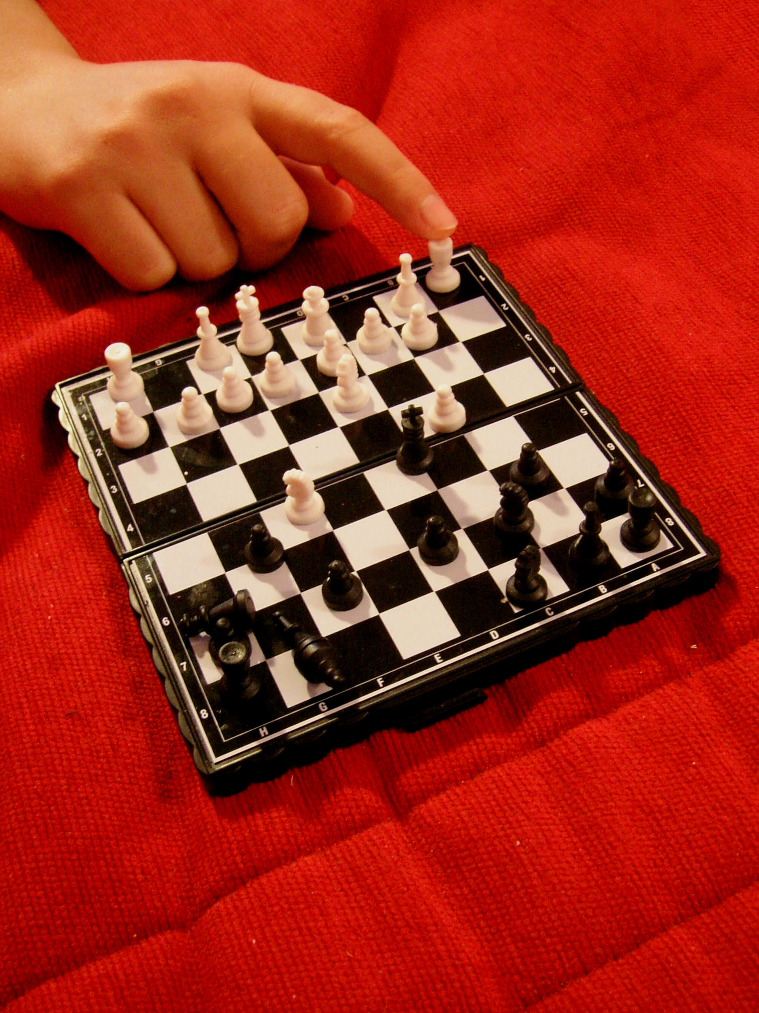 a hand moves a chess board with black pieces