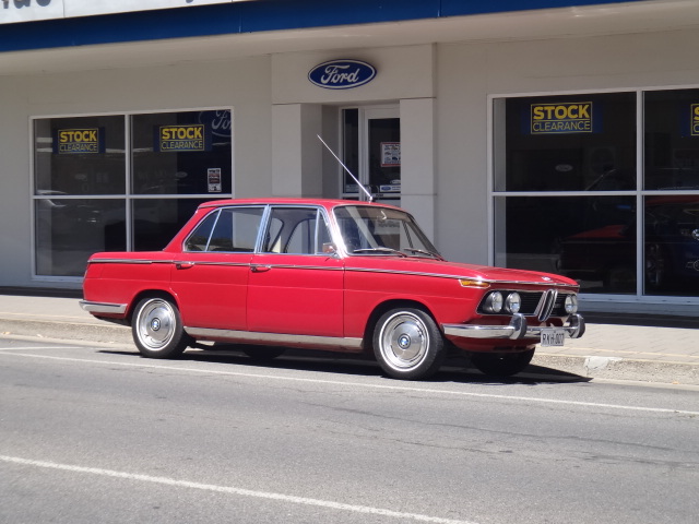 red classic car parked on street in front of store