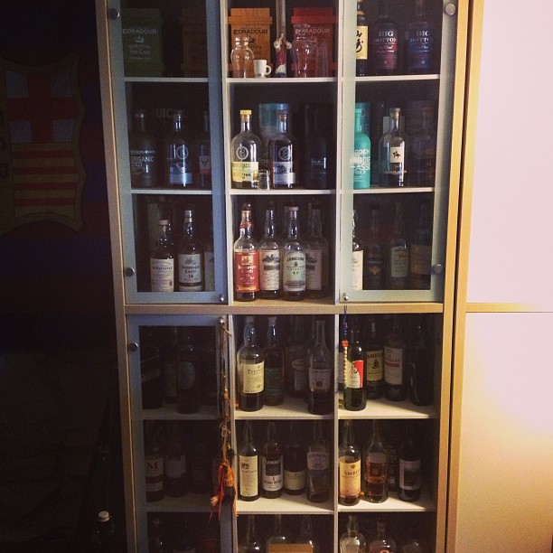a glass door cabinet with bottles in it