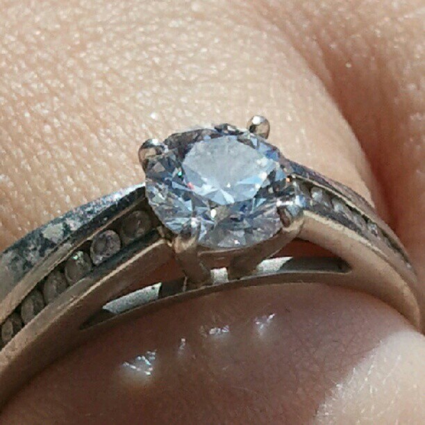 someone's wedding ring and engagement band with an aqua blue gemstone