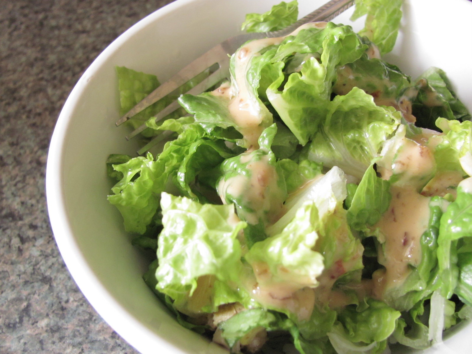 there is a salad with lettuce and dressing in the bowl