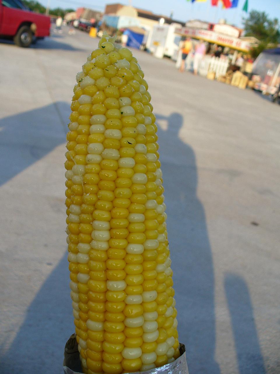 an ear of corn on a stick in a city street