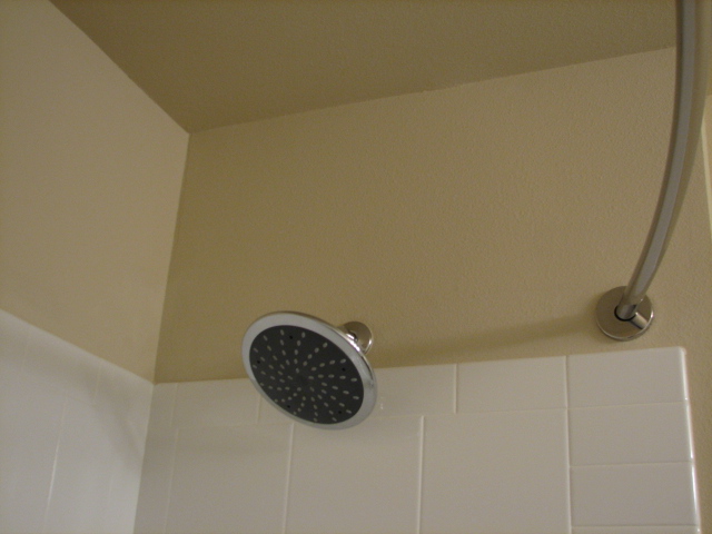 a shower head with a white tile wall behind it