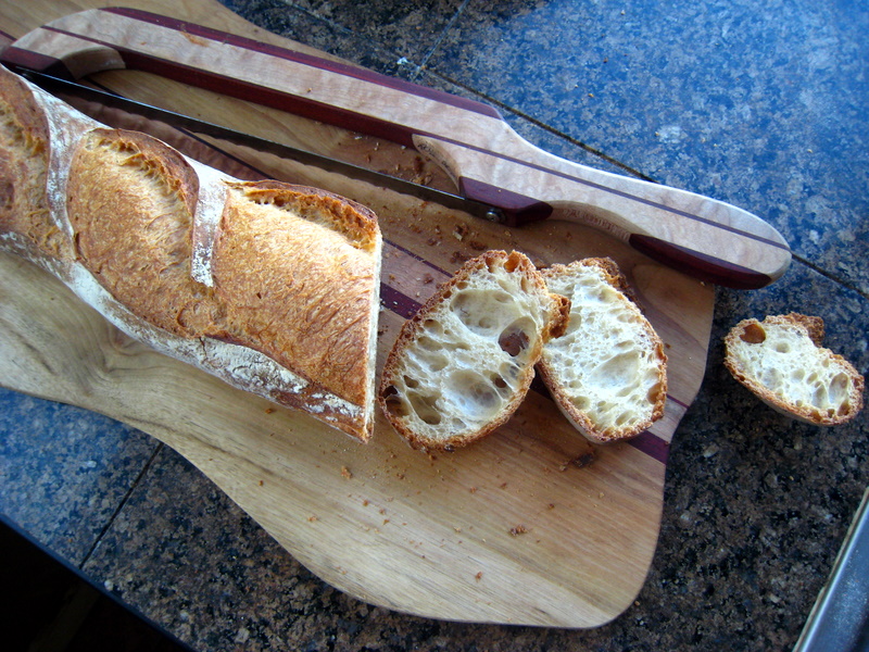 a piece of bread is cut up on a  board with a knife