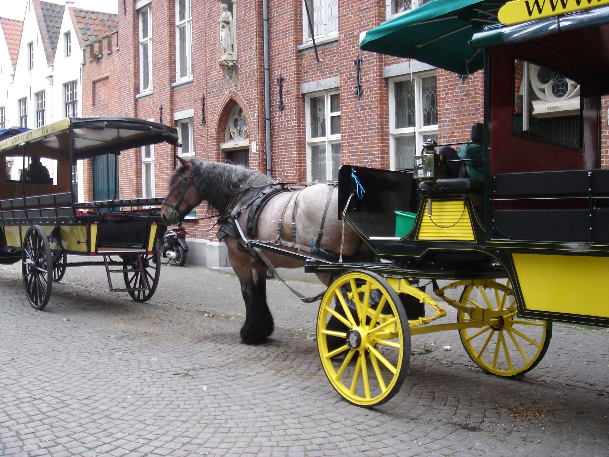 a horse pulling a buggy with a couple of yellow wheels on the road